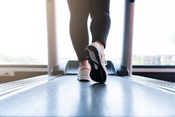 Fototapeta na wymiar Close up female feet wearing sneakers running on treadmill at fitness gym. Diet lifestyle, weight loss, stomach muscle, healthy concept.