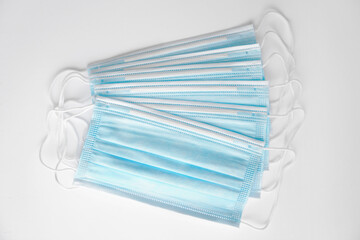 Blue medical masks lie on a white table - face mask against bacteria and viruses, top view, isolated