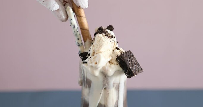 Decorating parfait with Oreo cookies and ice cream and biscuits