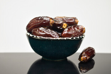 Medjool dates in a bowl on a black glossy table