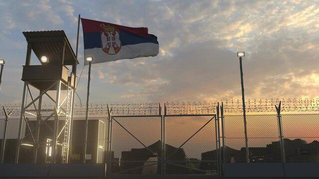 Waving flag of Serbia above military base in the evening