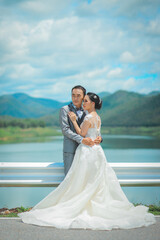 Fototapeta na wymiar Prtrait of Asian bride and groom with beautiful landscape of dam and mountain
