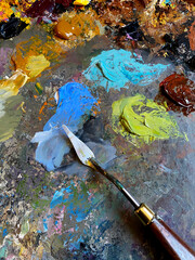 Artistic background. Oil paint palette knife spatula. Textured paint smudge stroke. Art color mixing with palette knife closeup. Paint stains. Multicolor tones, colours blend for artist painting.