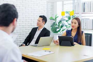 Attractive Asian Business woman note and discussing financial data and analyzing report on board at office with her manager. Teamwork meeting and partnership conference working concept.