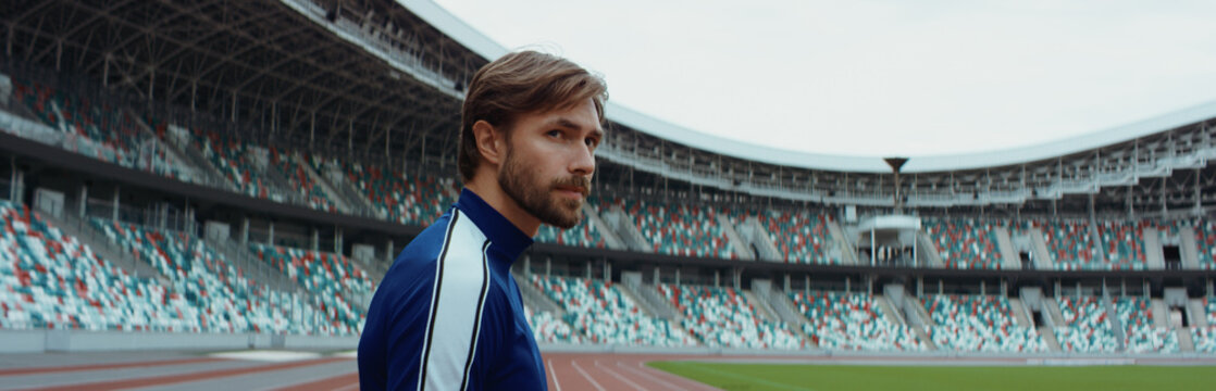 Young adult Caucasian male sportsman soccer player standing and admiring a large empty stadium - Powered by Adobe