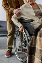 Obraz premium cropped view of senior man touching arm of handicapped, diseased wife in wheelchair