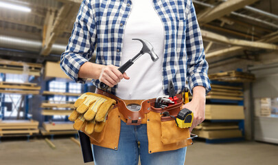 Fototapeta na wymiar industry, production and job concept - close up of woman or worker with hammer and working tools on belt over factory workshop on background