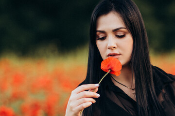 Beautiful long hair woman in a black dress in a poppy field