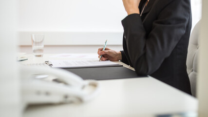 Businesswoman signing documents in a folder