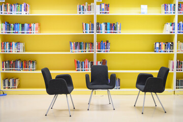 The black chair is located in the yellow library.