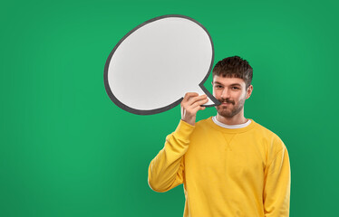 communication, mass media and people concept - happy smiling young man with speech bubble over emerald green background