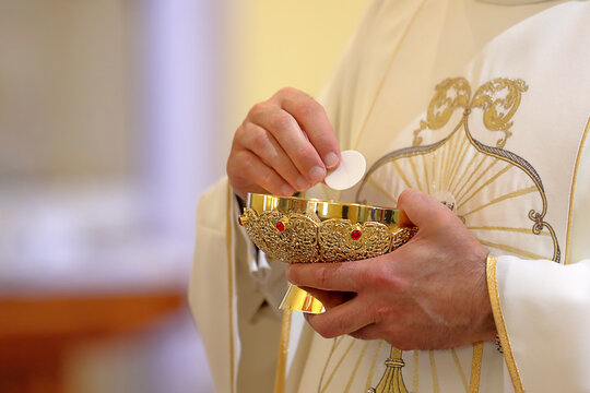 Holy host in the hands of the priest on the altar during the celebration of the mass