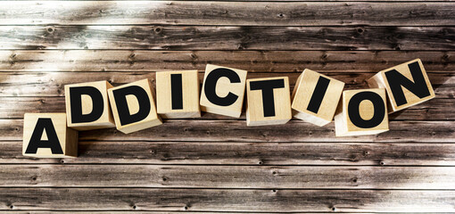 The word addiction made of wooden letters lies on a brown background