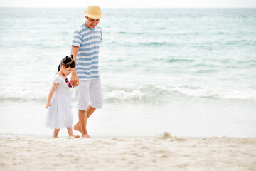 Relax Asian father with daughter walking on the beach