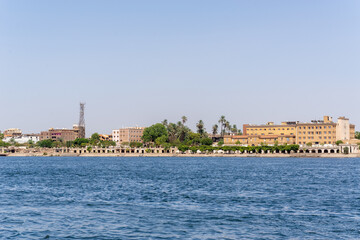 Fototapeta na wymiar Luxor, Egypt: Panorama of river Nile in Luxor city, view from a boat. Residental buildings and sailboats.