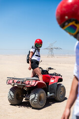 Fototapeta na wymiar Young woman in safari trip through Egyptian desert driving Quad/ATV. Quad/ATV safari trip in the desert near Hurghada, Egypt.