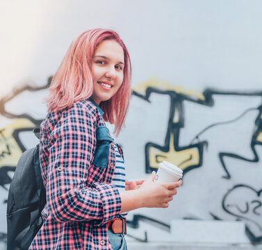 Cheerfully smiling Beautiful modern young female teenager Portrait with extraordinary hairstyle color in checkered shirt holding "coffee to go" cap.  Modern teens or cheerful students concept image