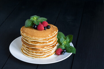 American classic pancakes with raspberry, black currant and mint on dark wooden background, selective focus, copy spase.