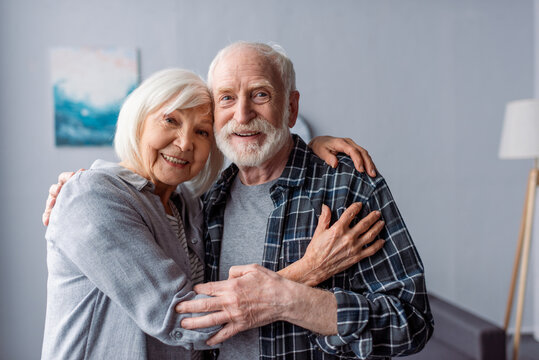 happy senior couple smiling and embracing while looking at camera