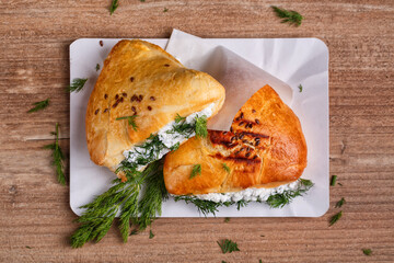 Fried pies with cottage cheese filling. Patties with cottage cheese and dill. Cheap recipe for homemade fried pies on a wooden background in rustic style. Close-up, top view.