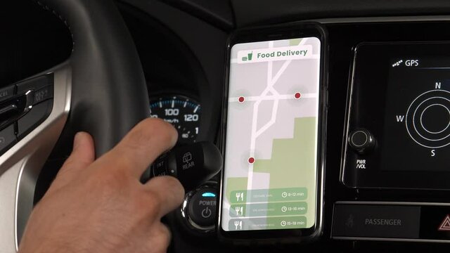 Smartphone app showing a meal delivery courier driver the next orders to deliver with his car. Mobile phone app concept of food delivery service.