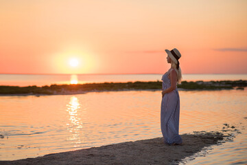 Fototapeta premium woman on the beach. woman on the beach at sunset. young woman in white dress on the beach