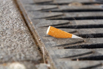 Cigarette stub lying on a metal grid