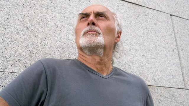 Serious senior athletic man leaning on wall