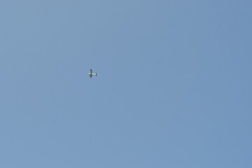 small plane flies against the blue sky