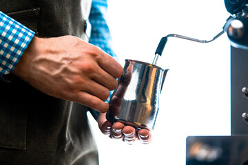 Professional Barista Warming Milk In Metal Jug With Steam Of Coffee Machine. Cappucino Or Latte Coffee Preparation At Home