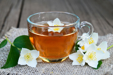Jasmine tea in a glass cup and fresh flowers on old wooden table.Healthy drink,diet or herbal medicine concept.Selective focus.