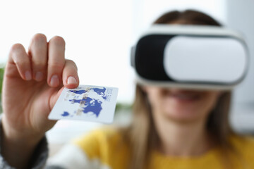 Close-up of woman in vr glasses holding white and blue plastic credit card. Female in virtual reality. Online shopping and payment. Modern innovative technologies concept
