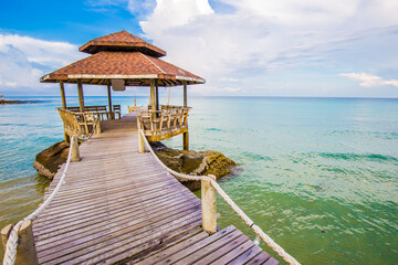 Wooden bridge to the sea beach with wooden hut blue sky