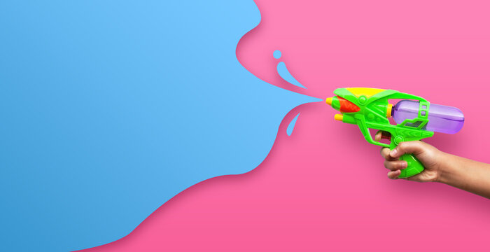 Hand holding plastic water gun on pink background