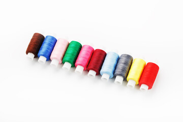 Colorful cotton craft sewing threads multicolored in a row isolated on a white background.