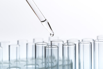 pipette with a drop and scientific laboratory test tubes in a research laboratory.