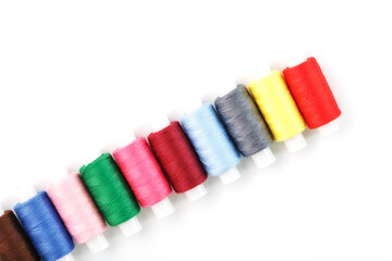 Colorful cotton craft sewing threads multicolored in a row isolated on a white background.