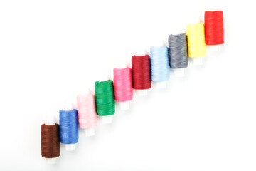 Colorful cotton craft sewing threads multicolored in a row isolated on a white background.