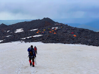 Fototapeta premium Two climbers with backpacks are walking along a snowy trail. Beautiful mountain winter landscape
