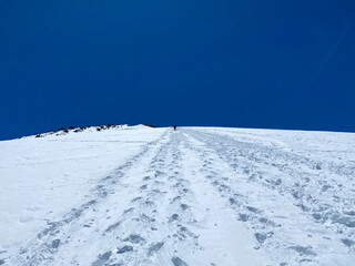 Fototapeta na wymiar Mountain Elbrus. A climber with backpacks and trekking poles walks along a snowy path.