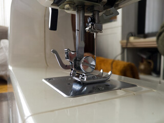 Compact electric sewing machine on the table in the living room.