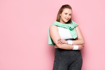pretty overweight girl with sweatshirt over shoulders smiling at camera on pink