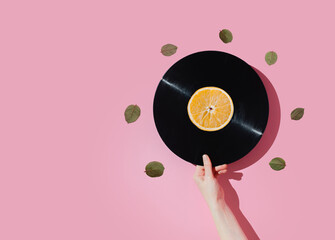 Vinyl record and citrus, orange on a pastel background. Fun concept of good mood.