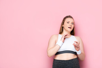 scared overweight girl gesturing while looking at camera on pink