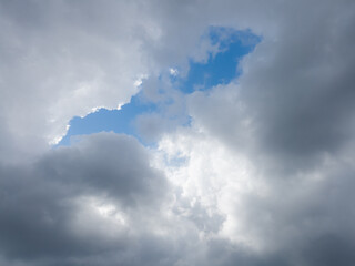 Through the crack in the gloomy clouds, a blue sky can be seen, beautiful clouds of abstract shapes.