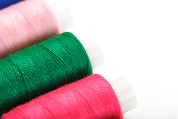 Sewing threads of different colors on reels on a white background. Free space, close-up. Isolate