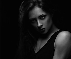 Beautiful makeup female model with long hair looking sexy on black background in darkness. Closeup...