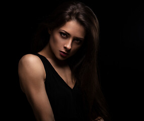 Fototapeta na wymiar Beautiful makeup female model with long hair looking sexy on black background in darkness. Closeup portrait. Art