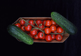 cucumbers and tomatoes in a box on a black background