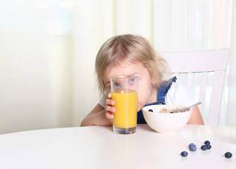 Child have a meal,kid have a fun hide behind glass of orange juice.